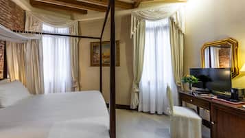 Ein Hotelzimmer mit einem großen Bett, einer Holzbalkendecke, einem Schreibtisch mit Fernseher und Vorhängen.