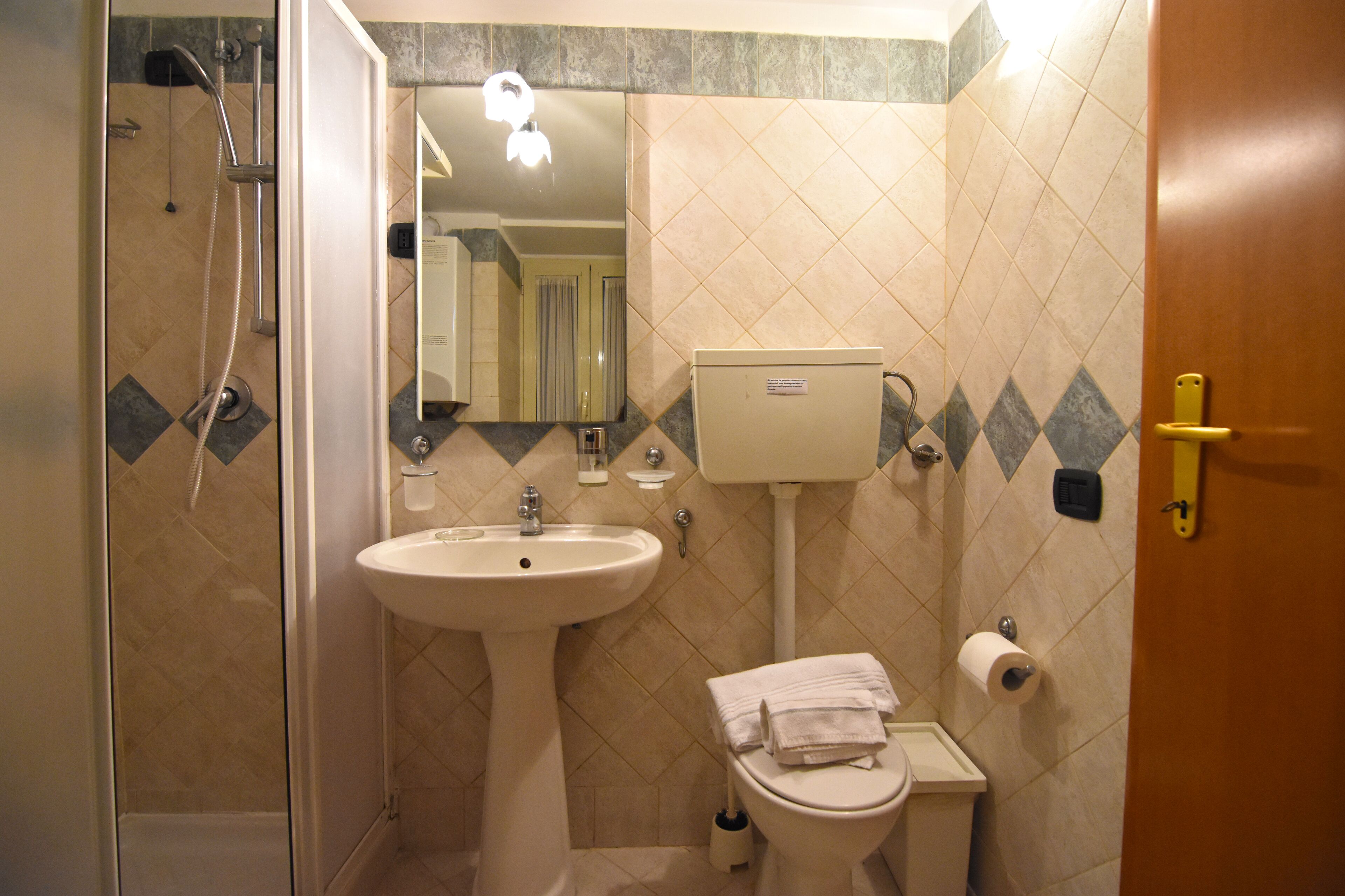Ein Badezimmer mit Dusche, Waschbecken, Toilette und Spiegel.