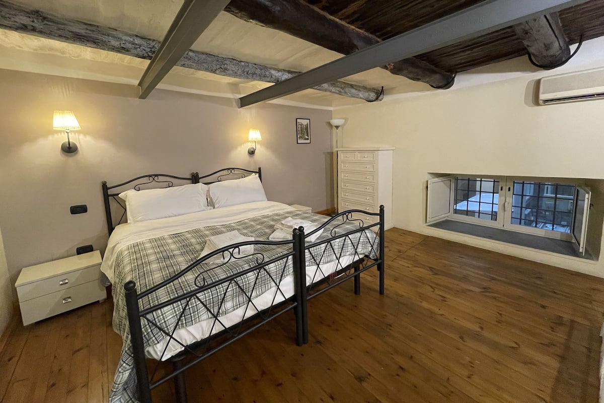 Une chambre à coucher avec un lit, des tables de chevet, une commode et une fenêtre donnant sur un beau paysage.