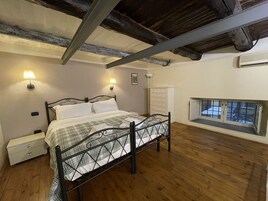 Une chambre à coucher avec un lit, des tables de chevet, une commode et une fenêtre donnant sur un beau paysage.
