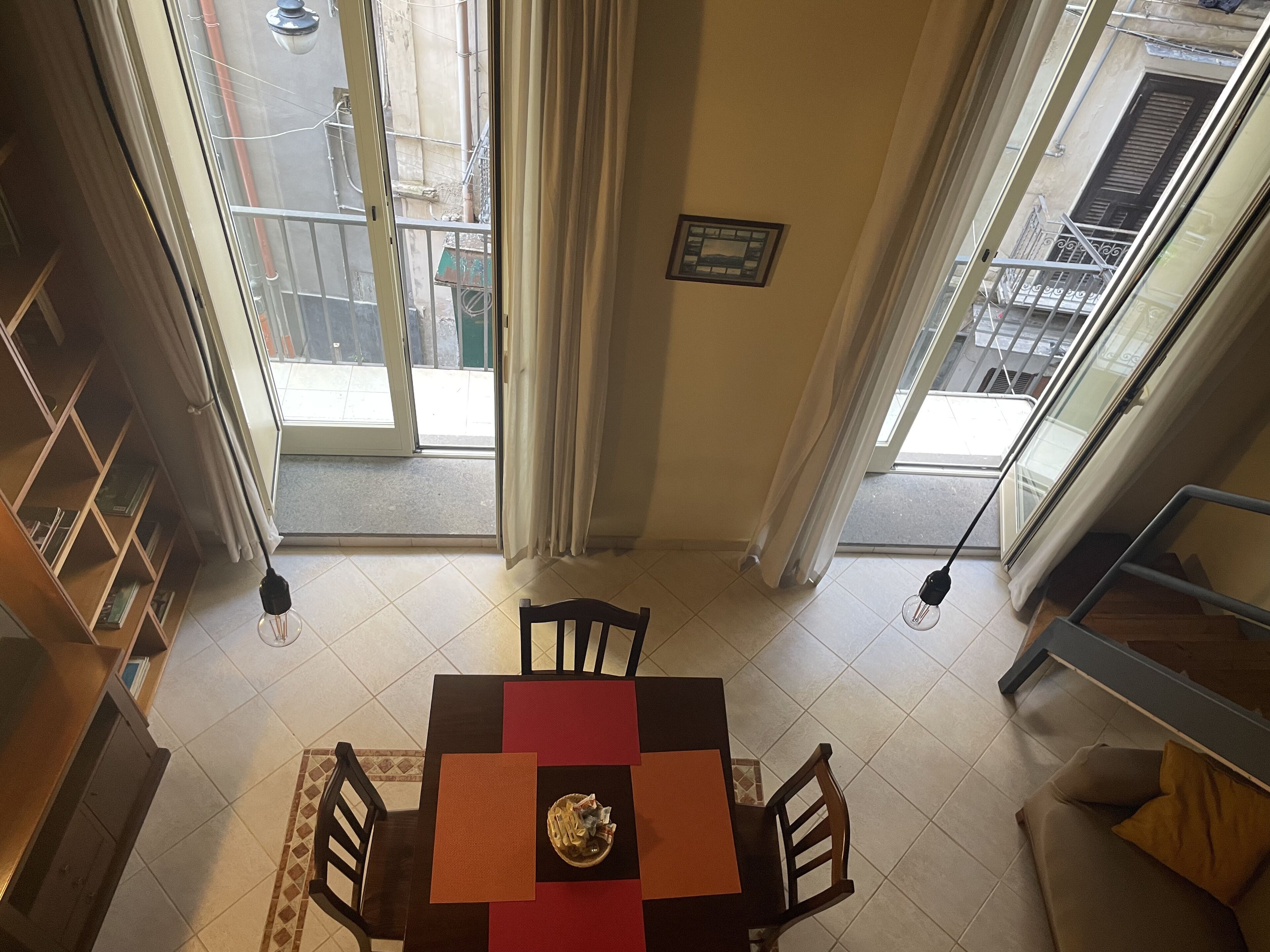 A dining area with a table and chairs, a sofa, and a view of the outside balcony.