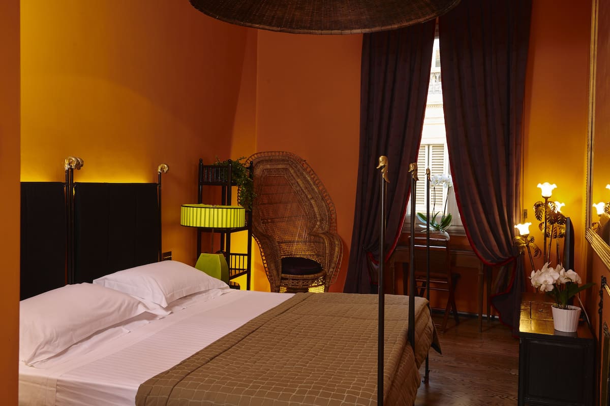 Una habitación de hotel con cama, una silla, un escritorio y un espejo.