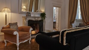 Un salon avec une cheminée, un canapé, un fauteuil et une lampe.