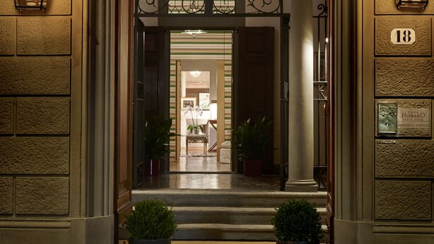 L’entrée d’un hôtel, avec une porte en arc de cercle, deux plantes en pot et une plaque indiquant le numéro de l’établissement.