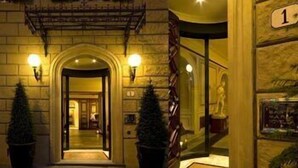 A hotel entrance with a stone facade, two potted Christmas trees, and a staircase leading to the upper floor. - Palazzo Vecchio (Florence)
