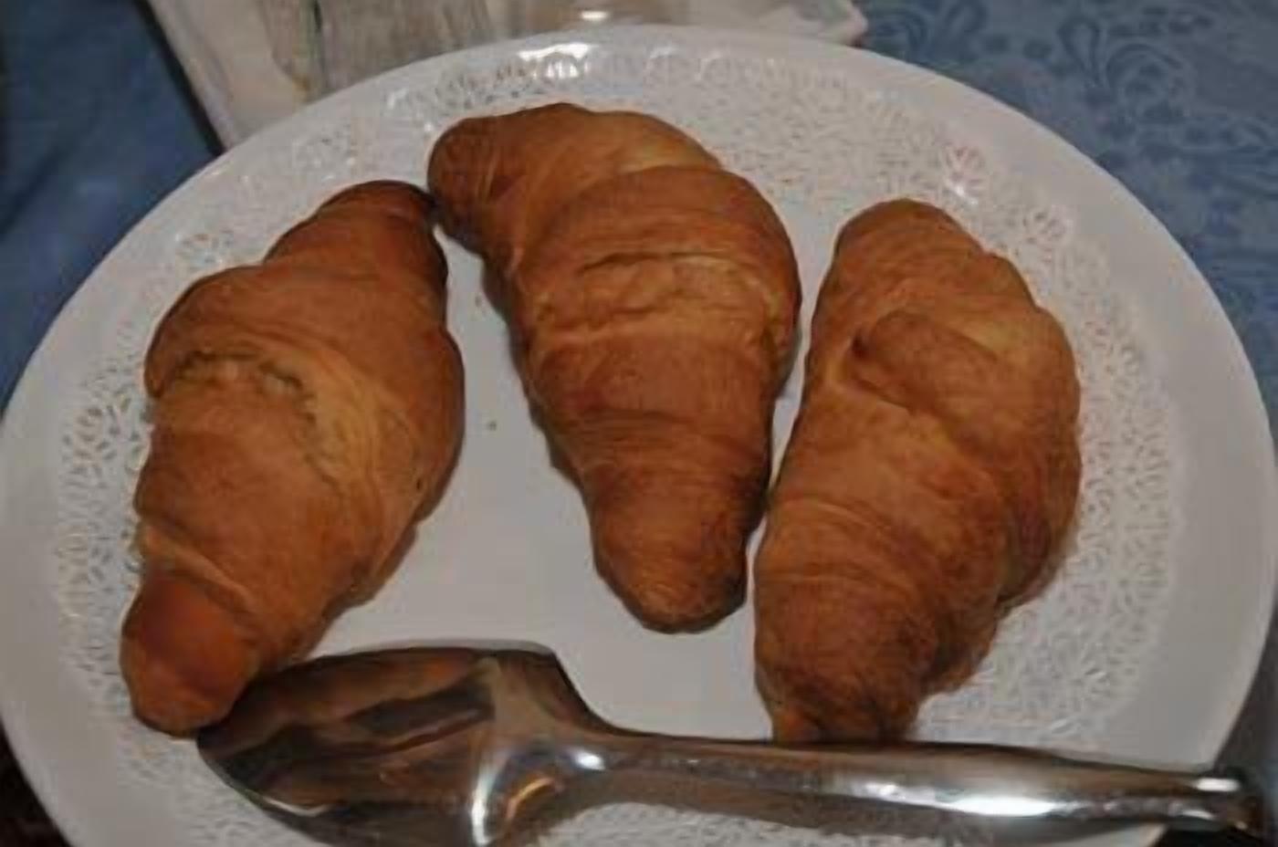 Un piatto con tre croissant e un cucchiaio.