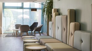 A modern lounge area with cushioned seating, a large window, and a hanging light fixture.