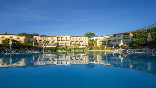 A hotel with a large swimming pool reflecting the buildings.