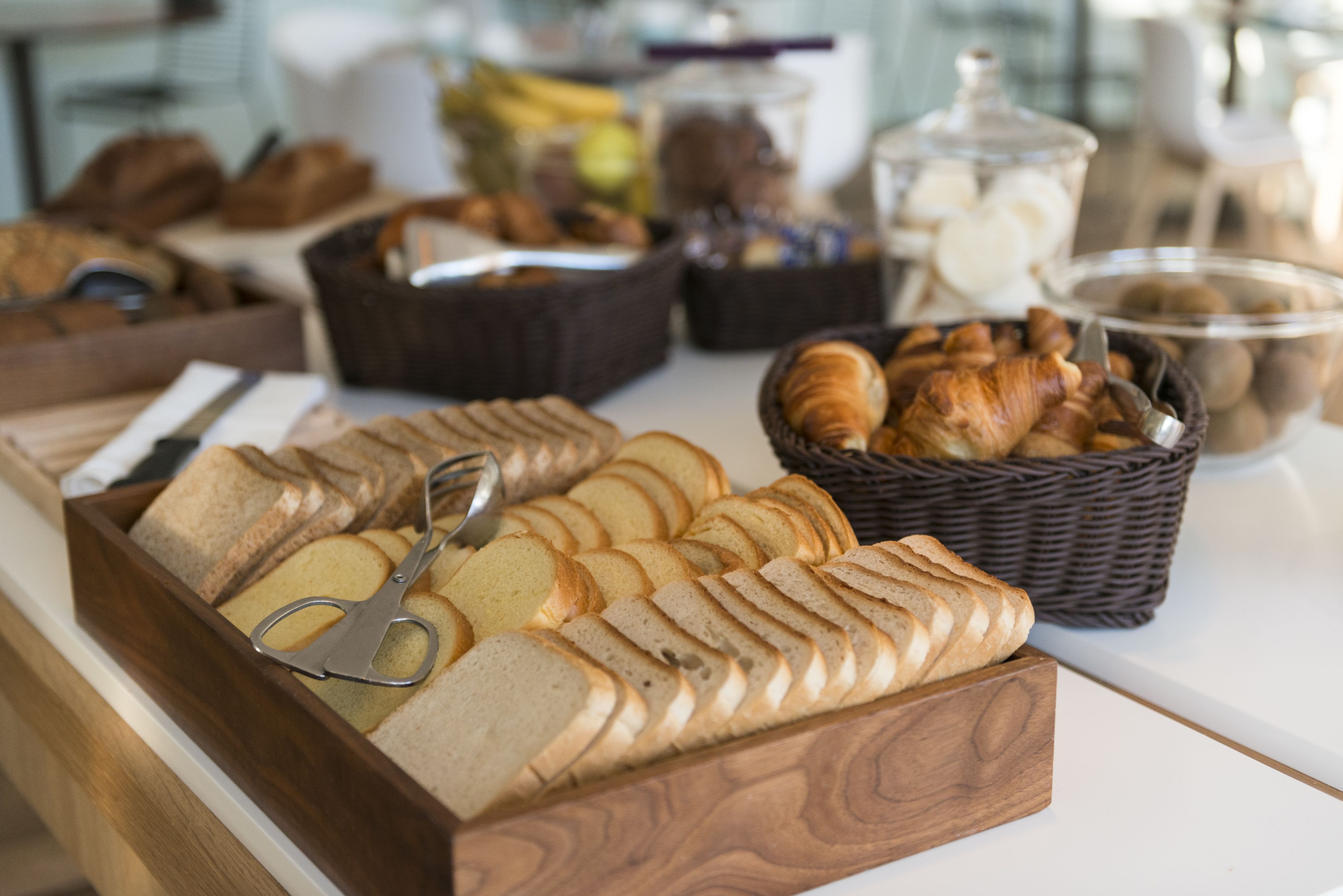 A breakfast buffet with various breads, pastries, and fruits.