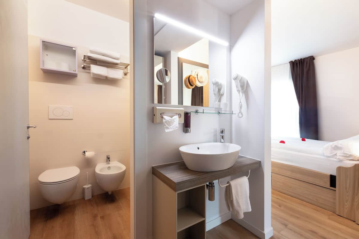 Une salle de bain moderne équipée de toilettes, d’un bidet et d’un lavabo, ainsi qu’une chambre avec un lit et une fenêtre.
