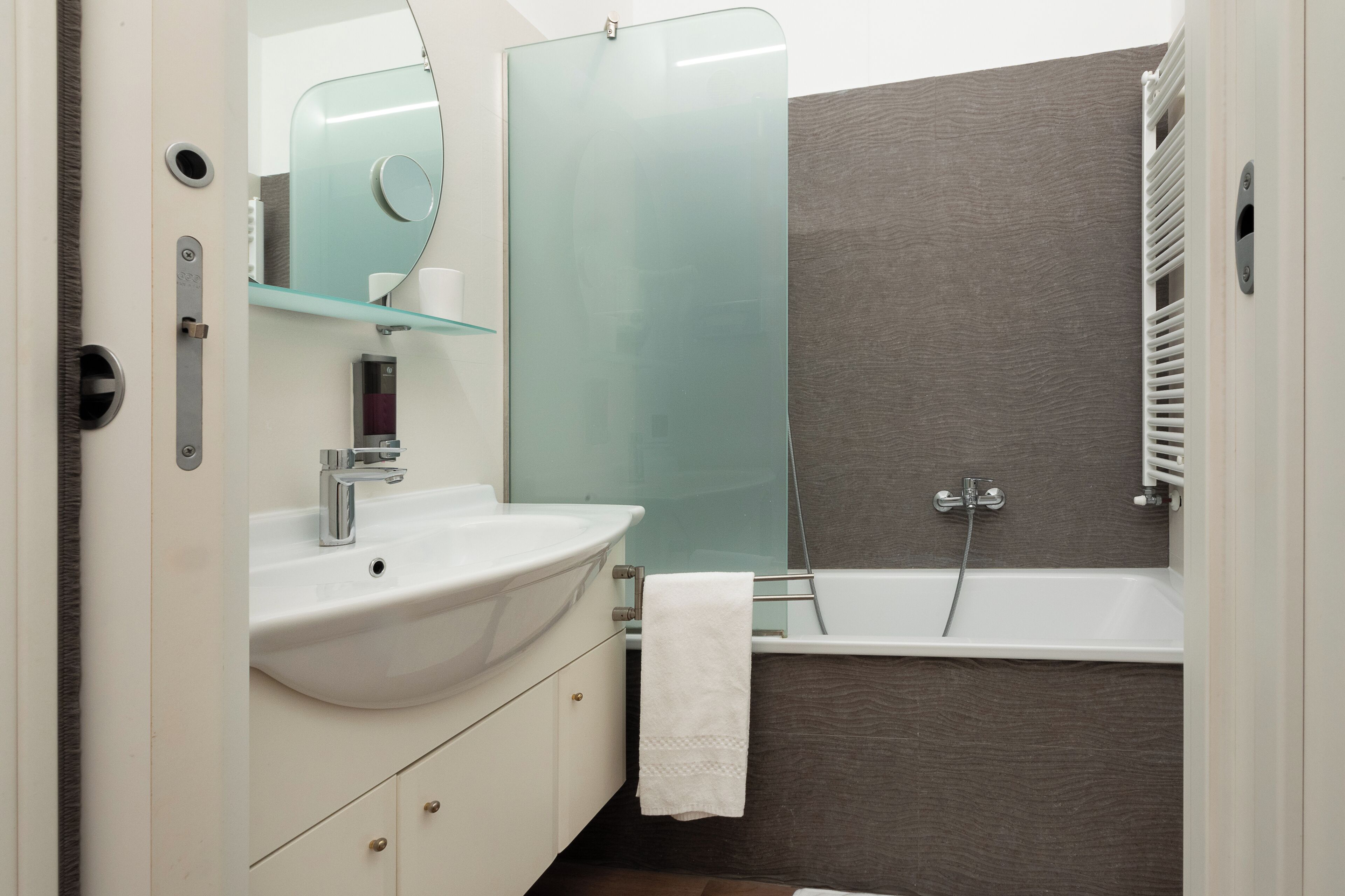 A modern bathroom with a white sink, glass shower enclosure, and a bathtub.