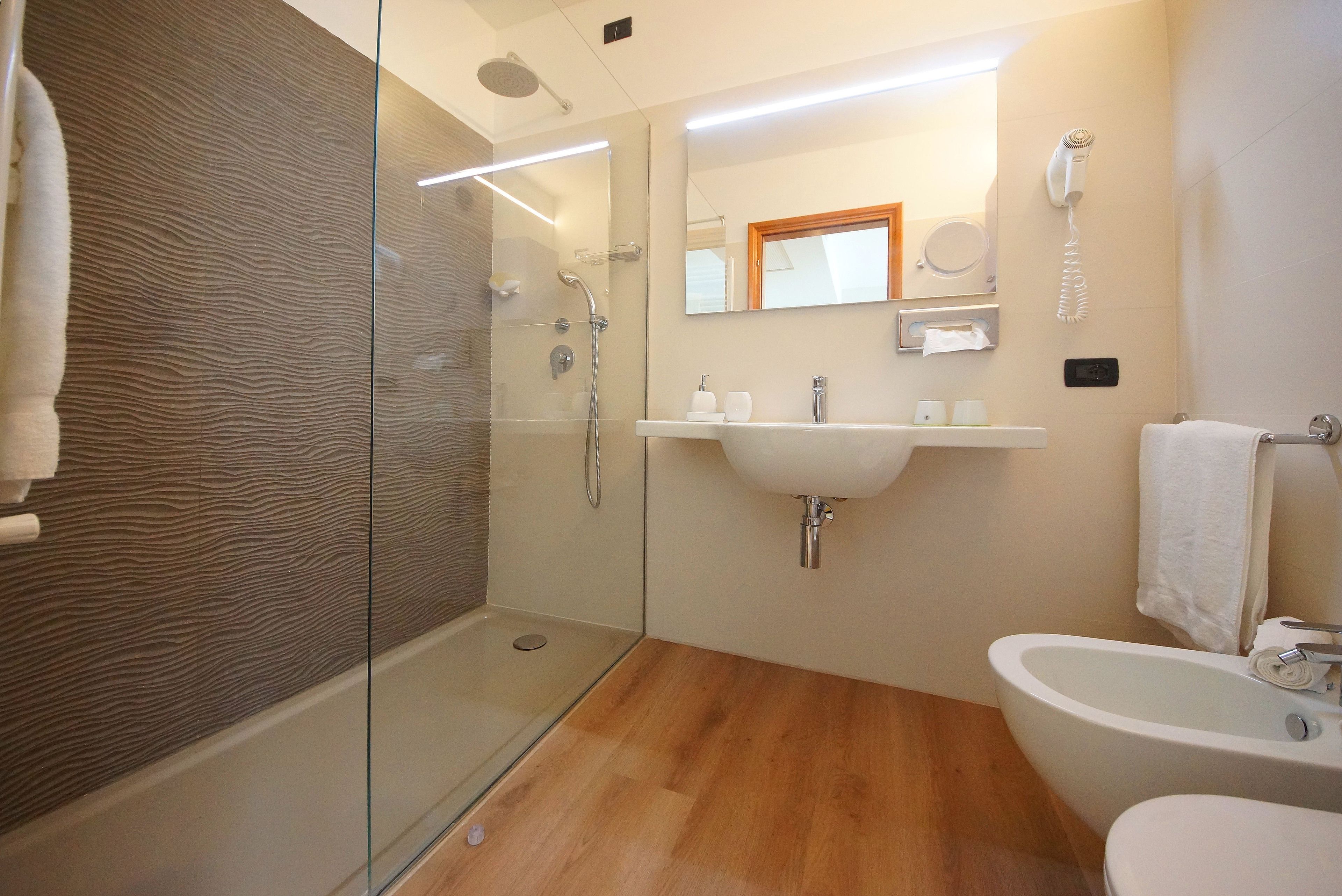 A modern bathroom with a glass-enclosed shower, a white sink, and a bathtub.