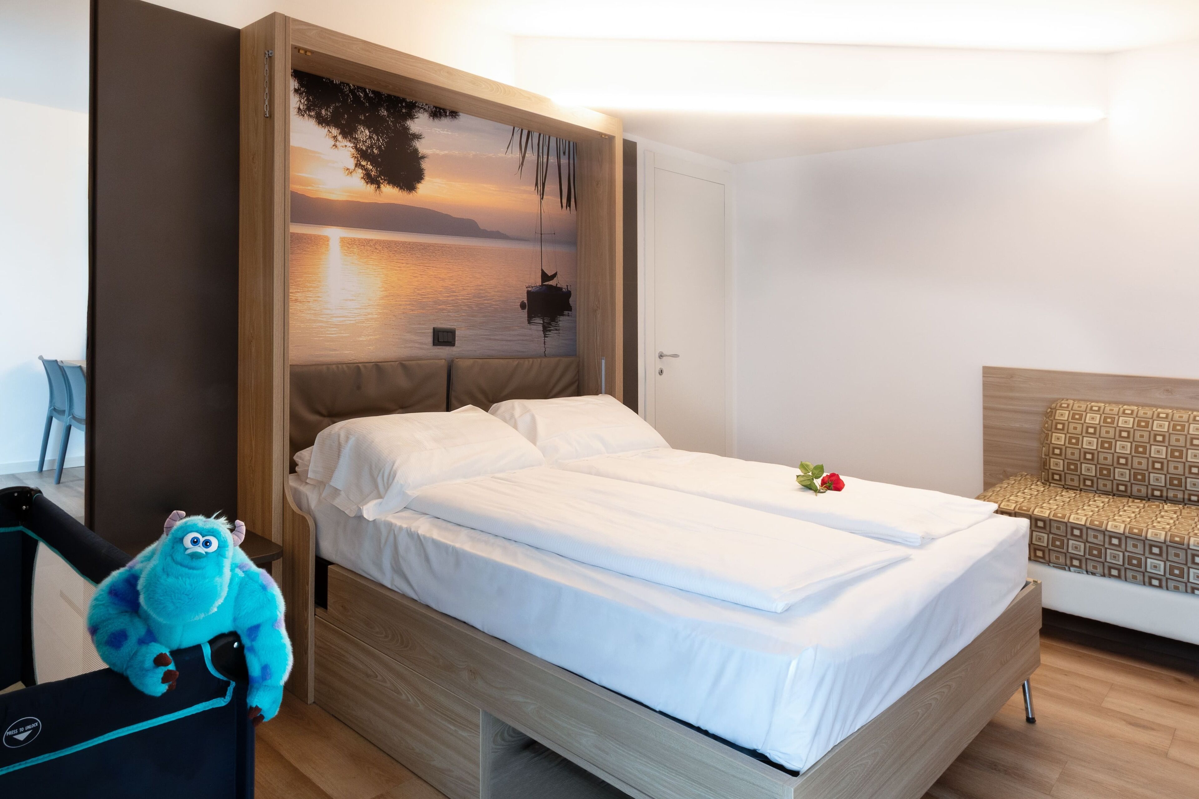 A hotel room with a bed, a nightstand, a wall-mounted TV, and a plush toy.
