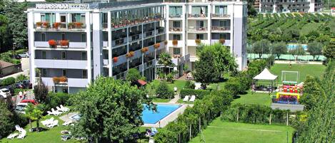 Un hotel de varios pisos con balcones, piscina y un jardín.