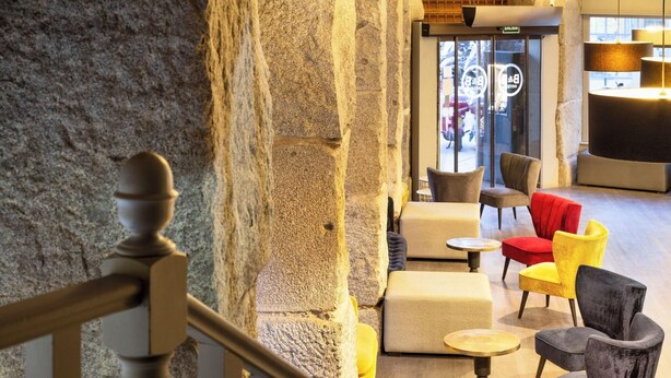 A lobby with stone walls, a staircase, and seating areas with various chairs and tables. - B&B Hotel Madrid Centro Plaza Mayor (Madrid)