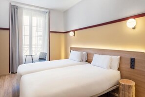 A hotel room with two beds, a small table, and a chair. - B&B Hotel Madrid Centro Plaza Mayor (Madrid)