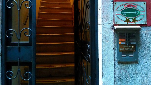 Escadaria que leva a uma porta com a placa do Albergo San Calvario.