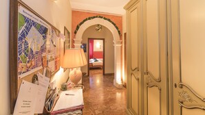 A hallway with a map on the wall, a desk with papers, and a bed in the background. - Aurora Rooms (Lecce)