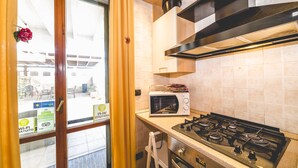 A kitchen with a gas stove, a microwave, and a window with a view of the outside. - Aurora Rooms (Lecce)