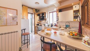 A modern kitchen with a central island, built-in appliances, and a dining area with a bar stool. - Aurora Rooms (Lecce)