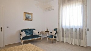 A room with a sofa, two chairs, a small table, and a window with curtains. - Casa Vacanza La Scisa (Alessano)