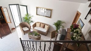 A spacious living area with a sofa, armchairs, and a coffee table. There are potted plants and a framed picture on the wall. - Casa Vacanza La Scisa (Alessano)
