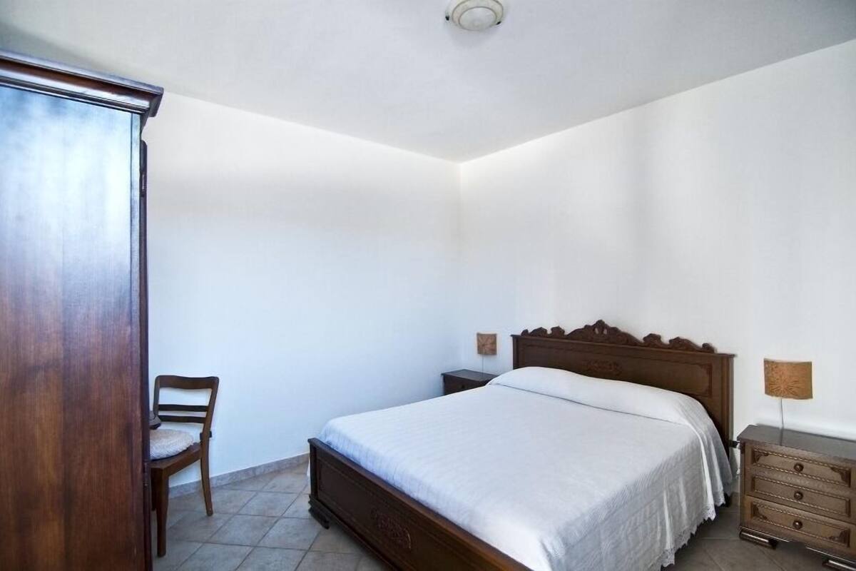 A bedroom with a wooden bed, a chair, a dresser, and a nightstand.