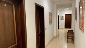 A hallway with wooden doors, tiled flooring, and artwork on the walls. - Hotel Bonazzi (Perugia)