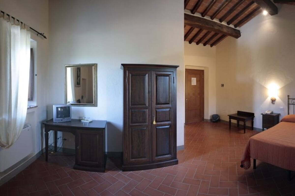 A bedroom with a bed, a desk, a wardrobe, and a mirror.