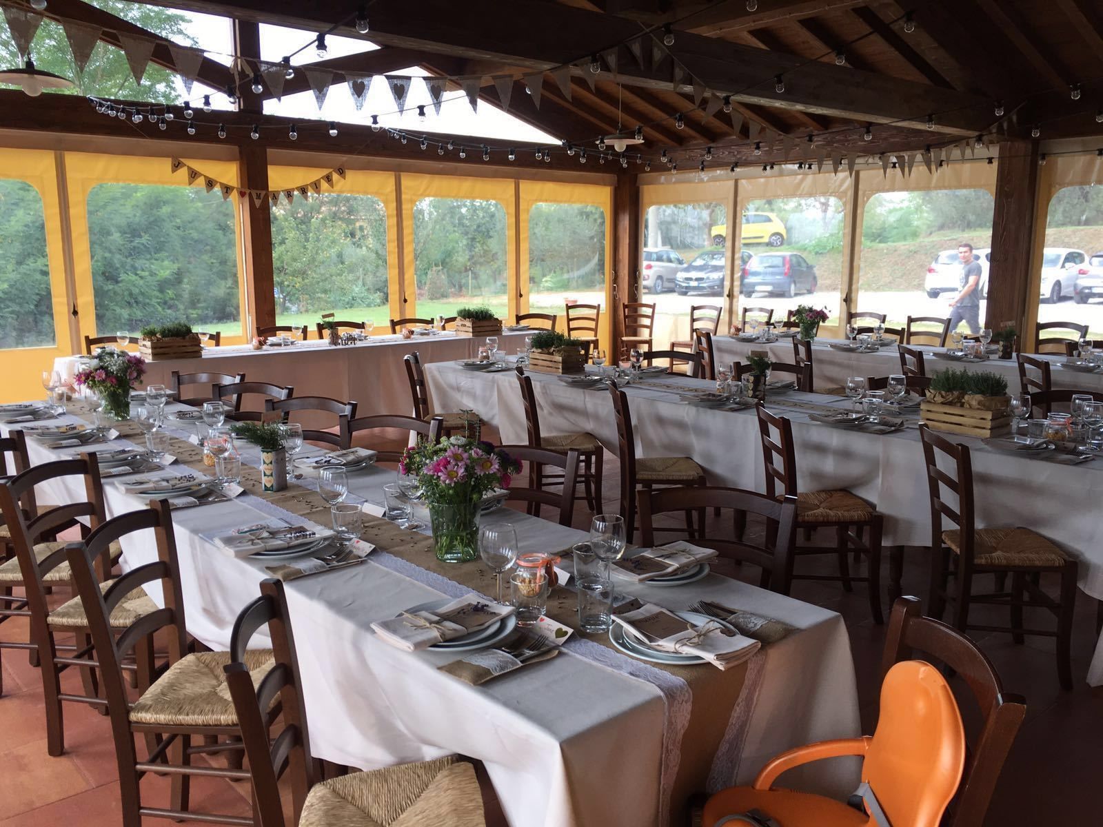 A restaurant with multiple tables set for dining, featuring white tablecloths and wooden chairs.