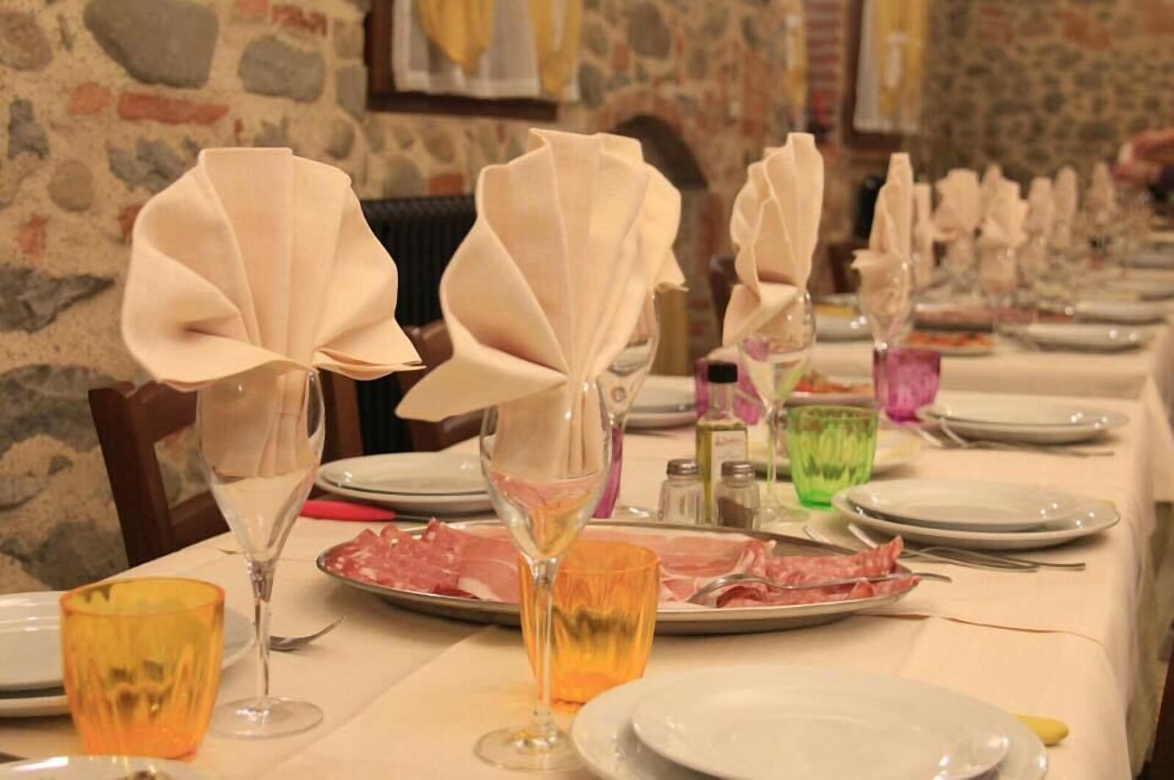 A dining table set with plates, glasses, and a bottle of wine.