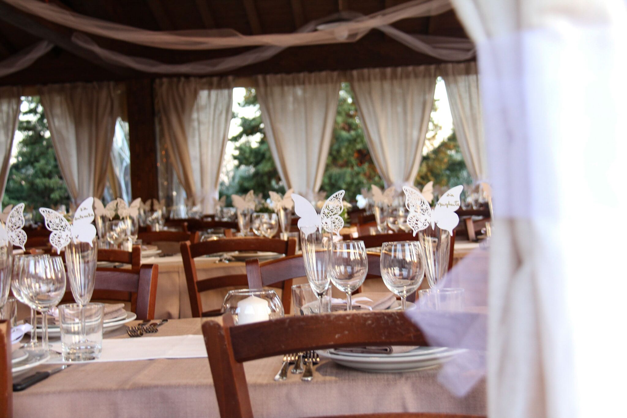 A dining area with tables set for a meal, featuring white tablecloths, glassware, and decorative butterfly cutouts.