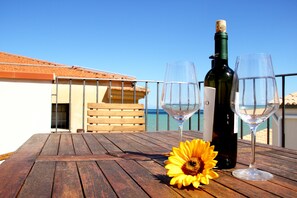A wooden table with a bottle of wine, two glasses, and a sunflower.