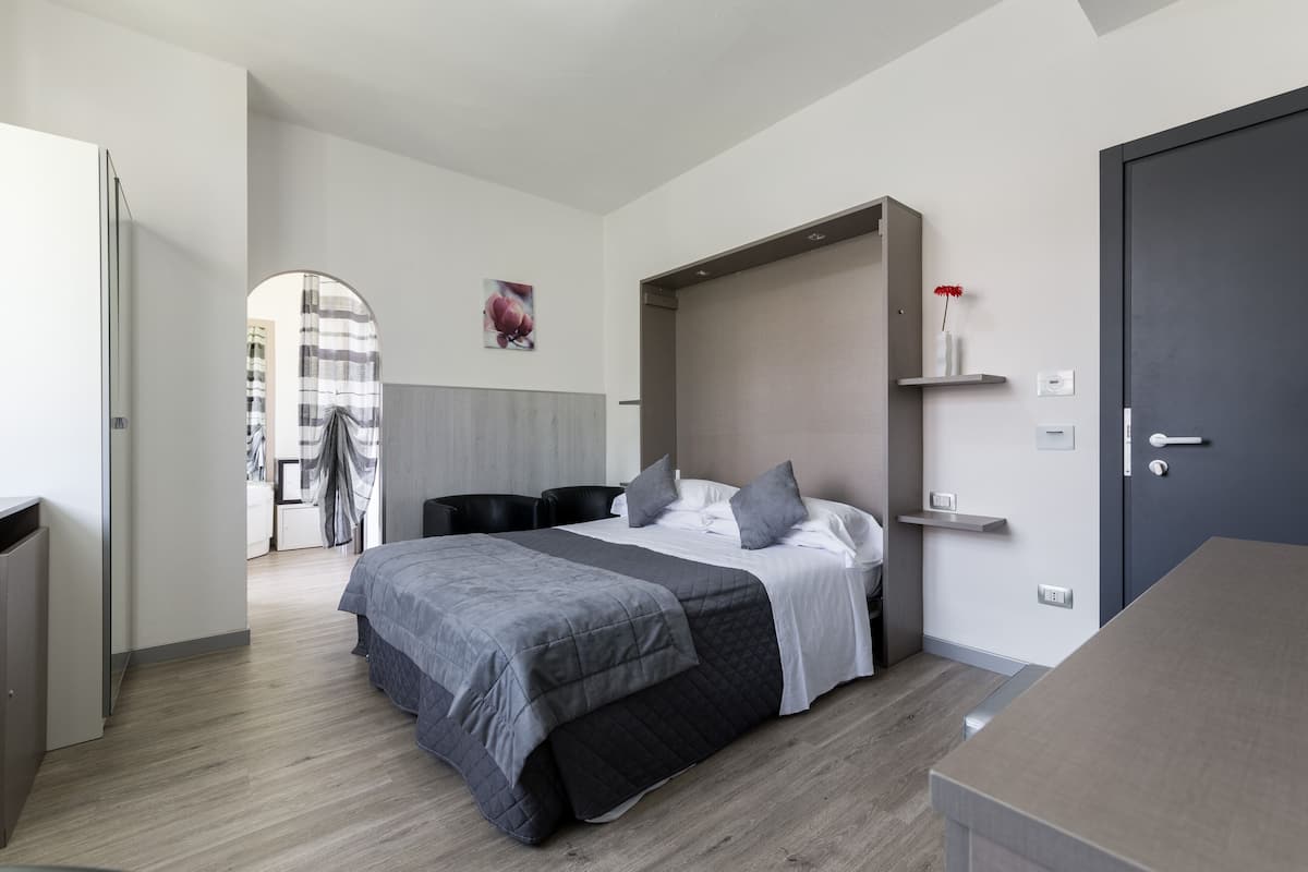 Un dormitorio moderno con cama, mesitas de noche, armario y puerta.
