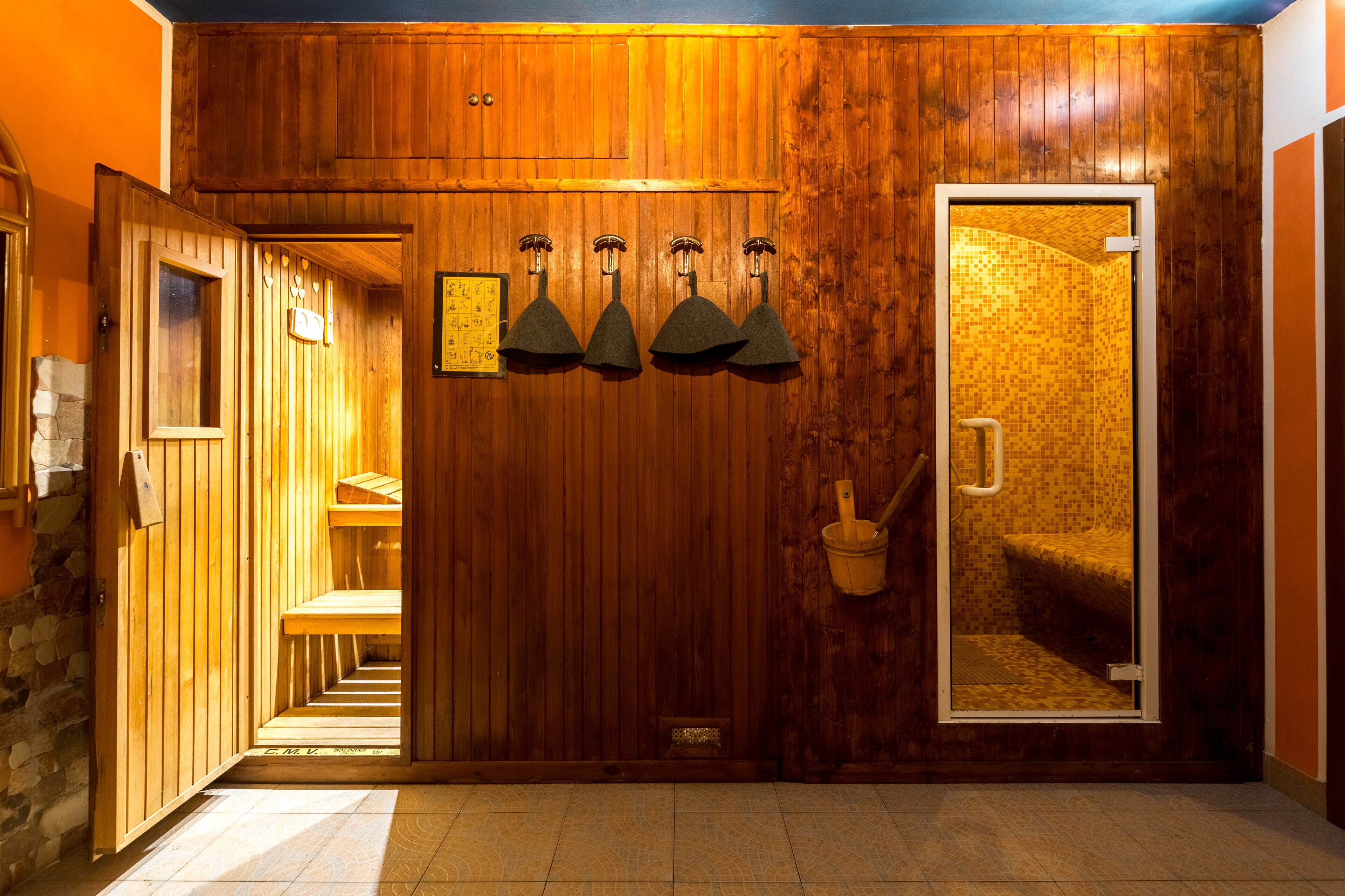 A wooden interior with a sauna room, wooden benches, and a wooden door with a tiled interior.