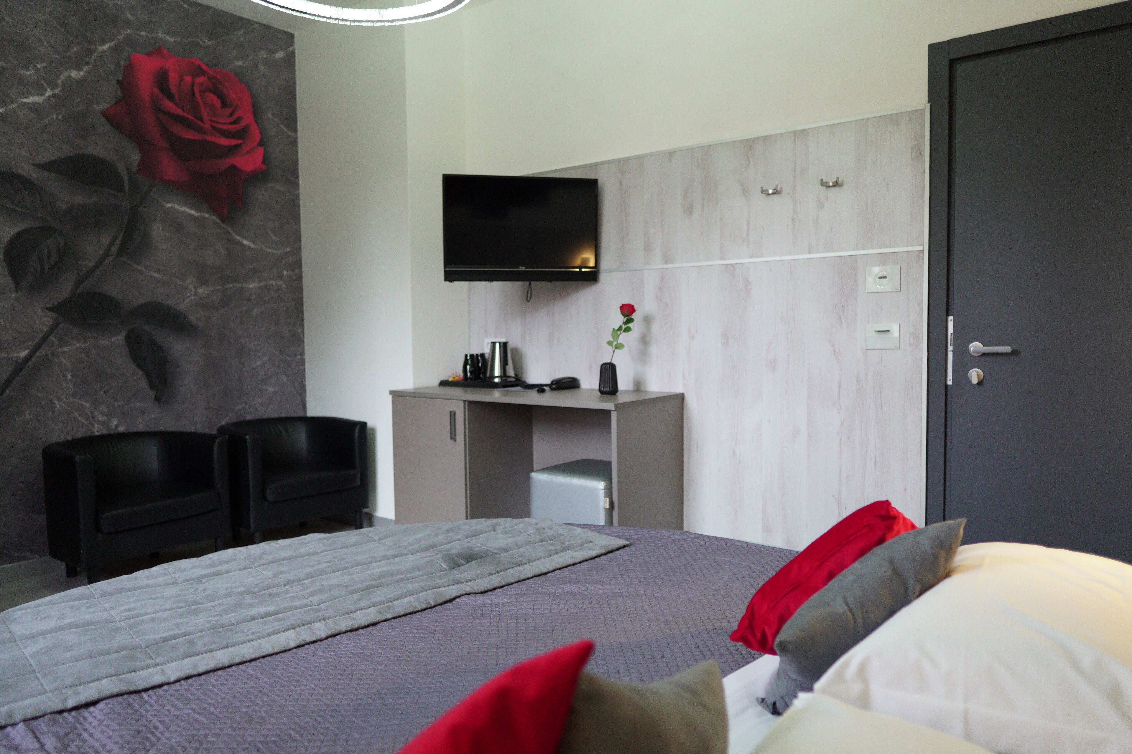 Quarto de hotel moderno com cama, escrivaninha, televisão e porta.