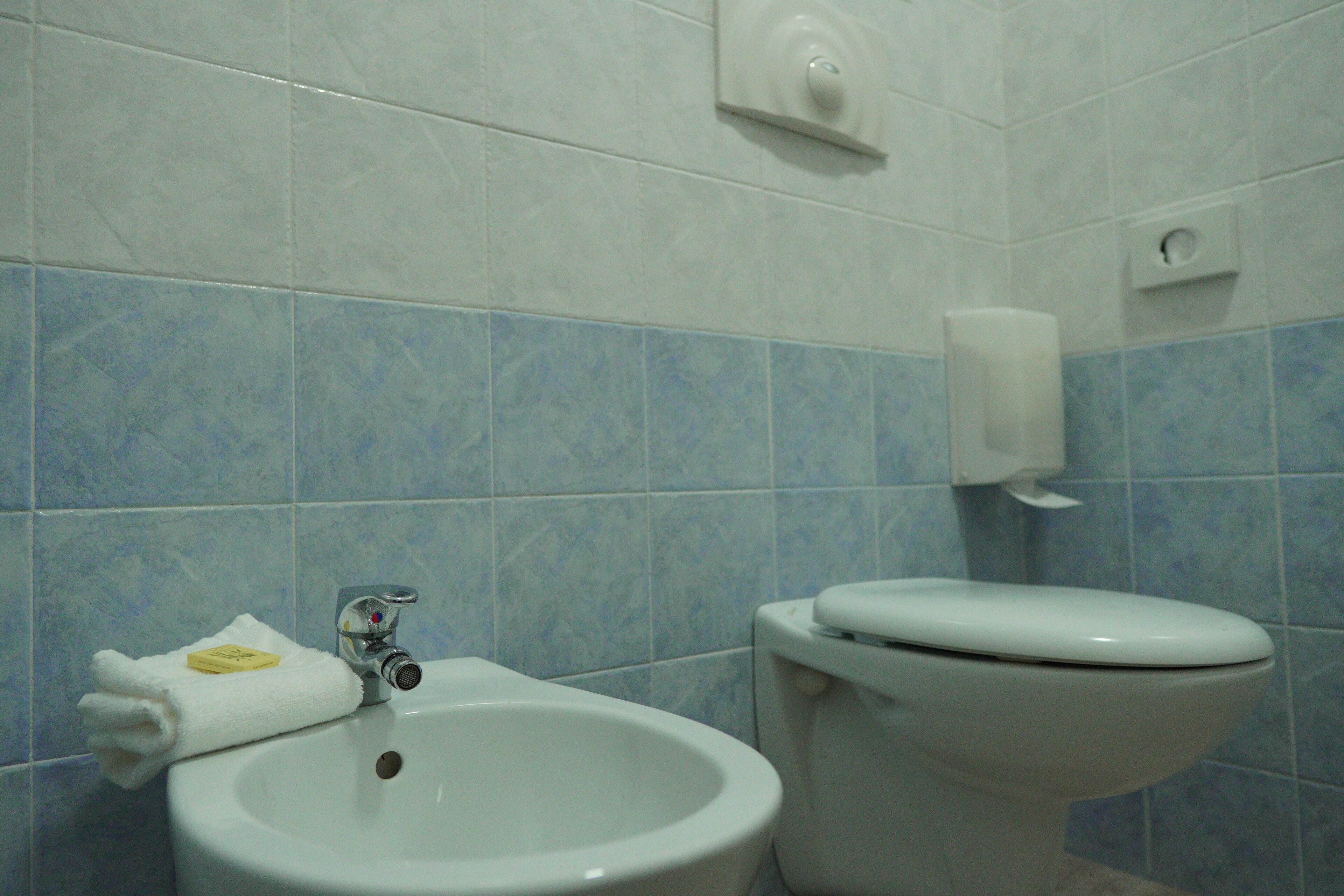 A bathroom with a sink, toilet, and blue-tiled walls.