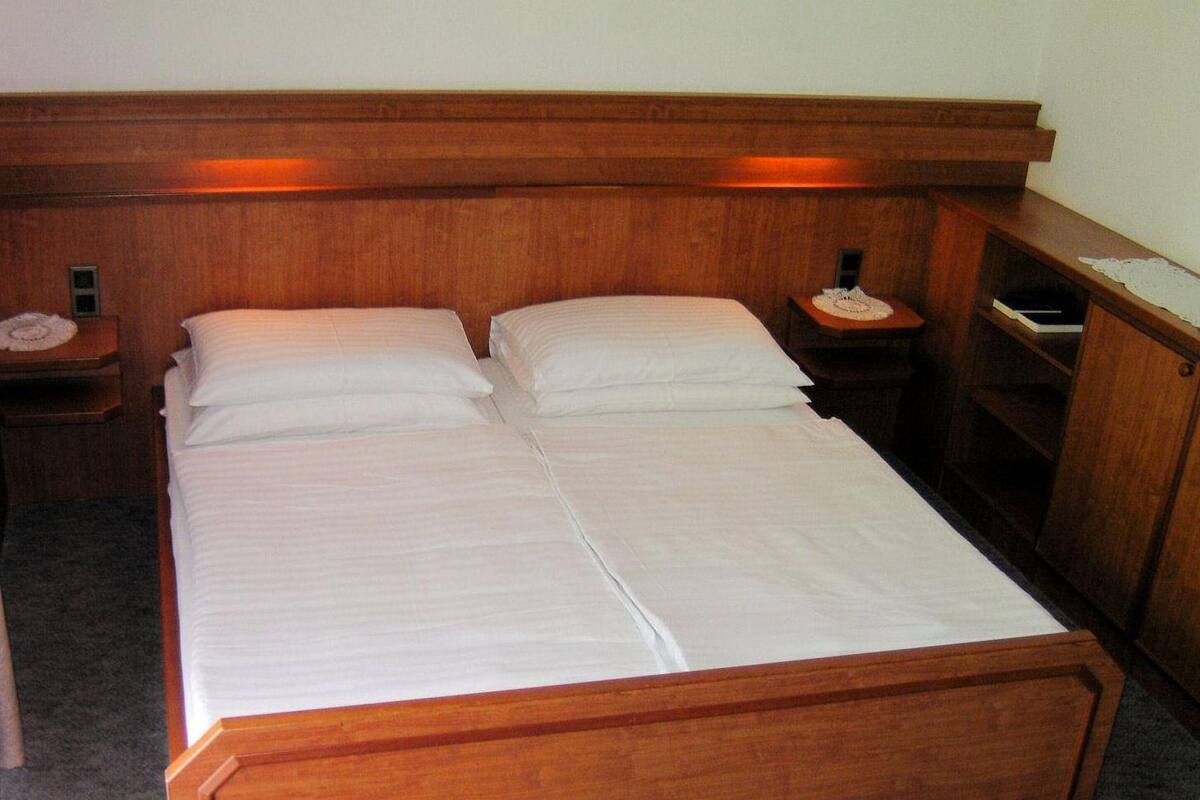 A double bed with a wooden headboard and two bedside tables, each with a lamp and a telephone.