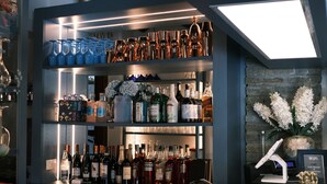 A bar area with shelves of bottles, glasses, and a cash register. - Hotel Sonenga (Menaggio)