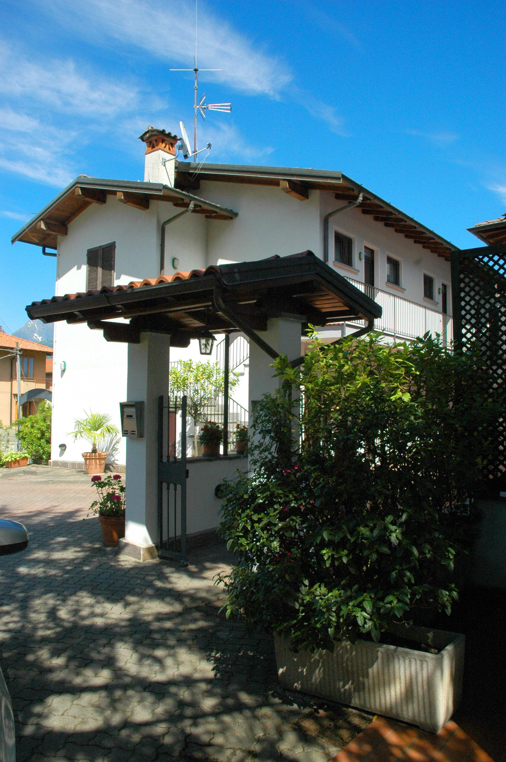 A building with a tiled roof, a pergola, and potted plants.