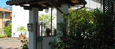 A building with a tiled roof, a pergola, and potted plants.