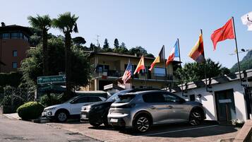A hotel with a reception area, parked cars, and multiple flags.