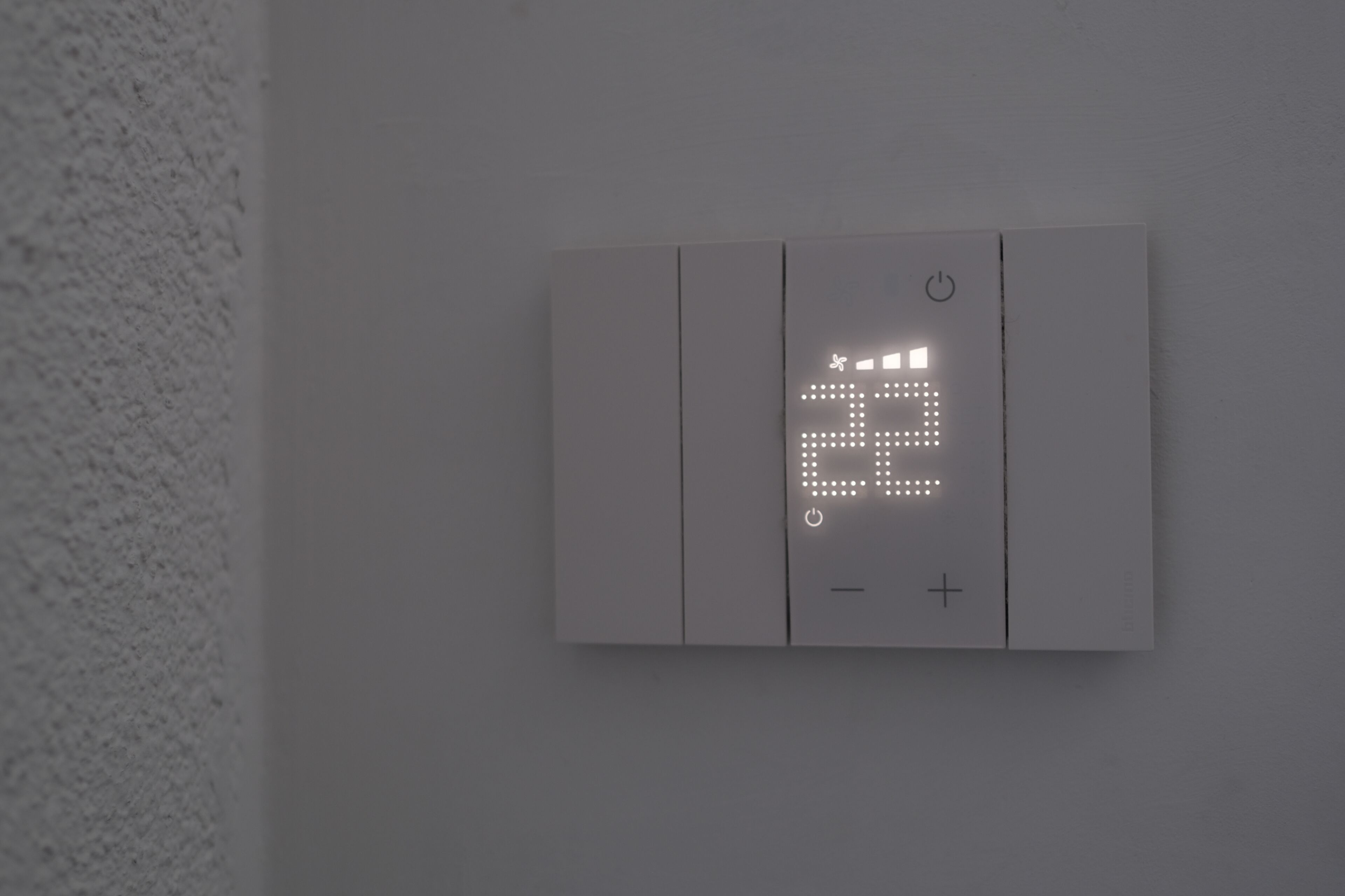 A wall-mounted thermostat with a digital display and control buttons.