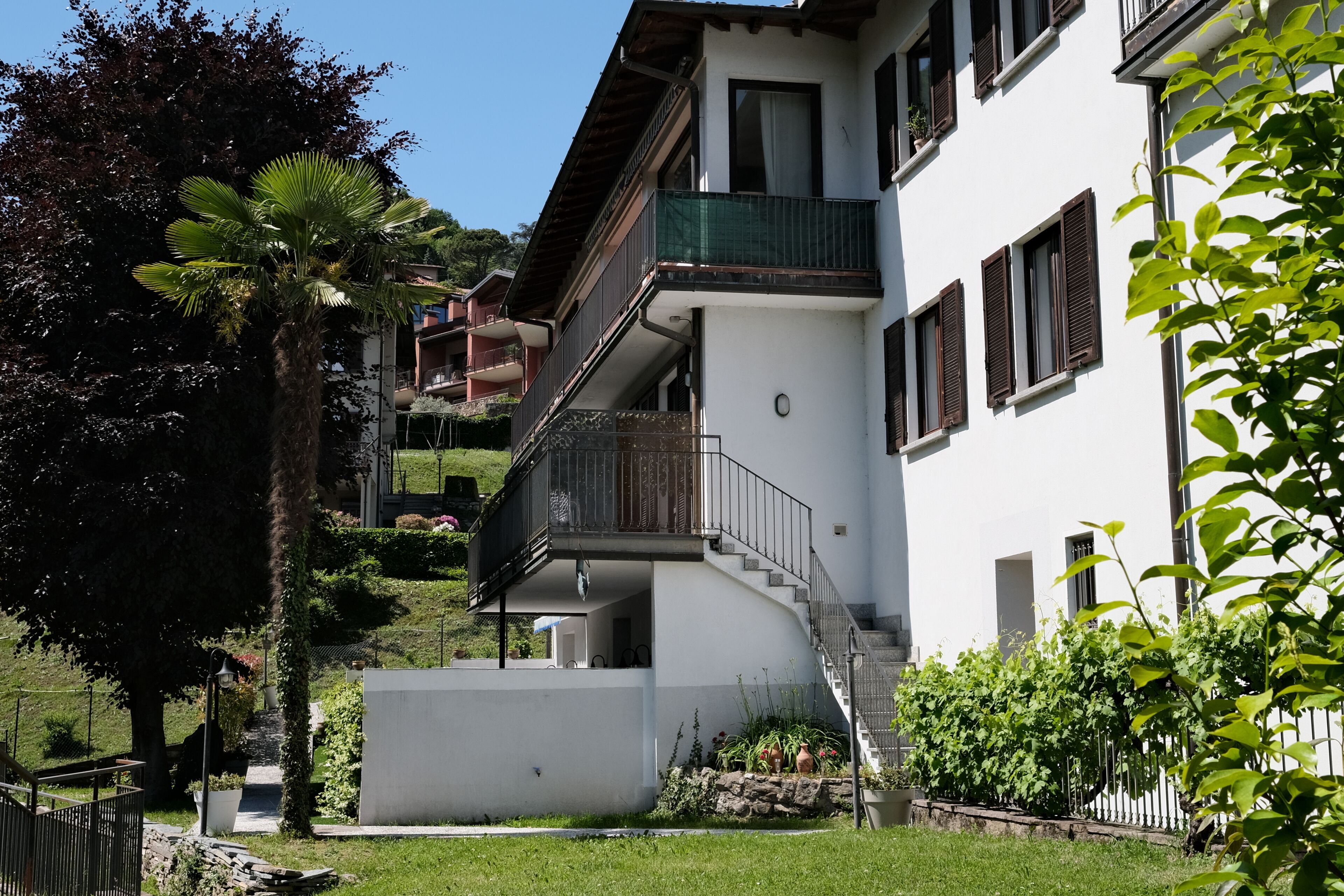 A multi-story building with balconies, a staircase, and a garden area.