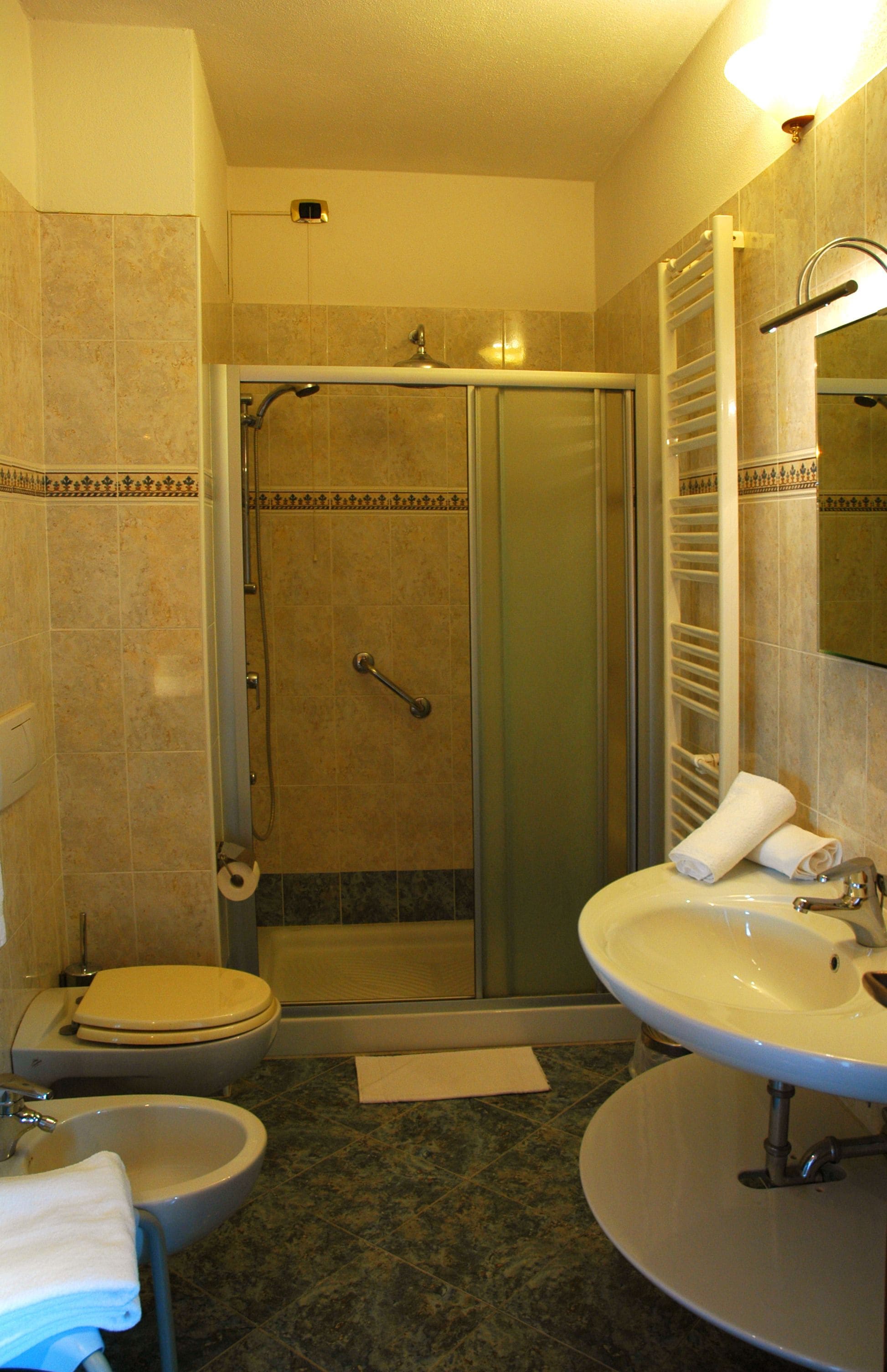 A bathroom with a shower, toilet, sink, and mirror.