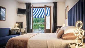 A hotel room with a bed, a desk with a chair, a television, and a view of the outdoors. - Hotel Sonenga (Menaggio)