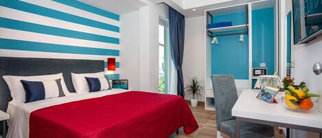 A modern hotel room with a bed, a desk, and a view of the outside.
