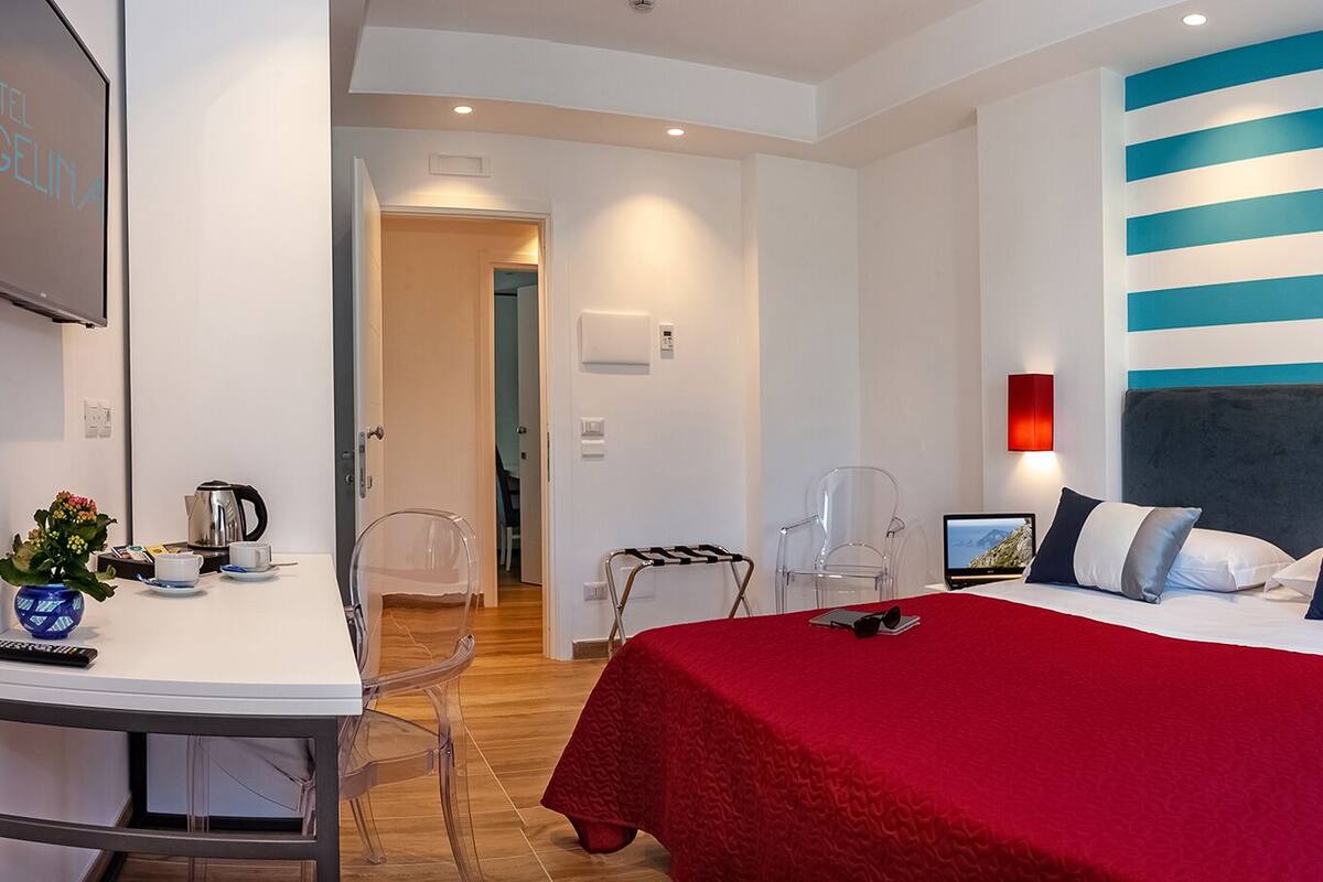 Una habitación de hotel con cama, mesitas de noche, escritorio y una silla.