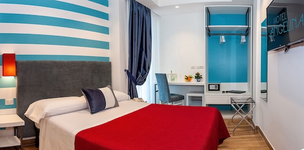 Una habitación de hotel con cama, escritorio, silla, televisor y espejo.