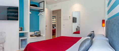 A hotel room with a bed, a desk with a laptop, a TV, and a wardrobe.